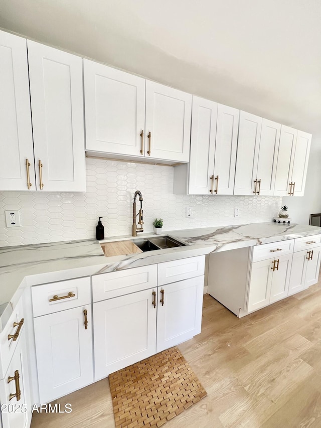 kitchen with backsplash, light hardwood / wood-style flooring, and white cabinetry