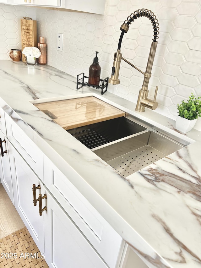 room details with white cabinetry, backsplash, and light stone countertops