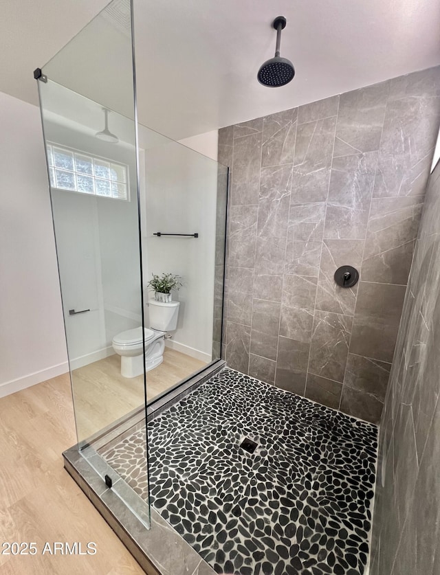 bathroom featuring hardwood / wood-style floors, a tile shower, and toilet