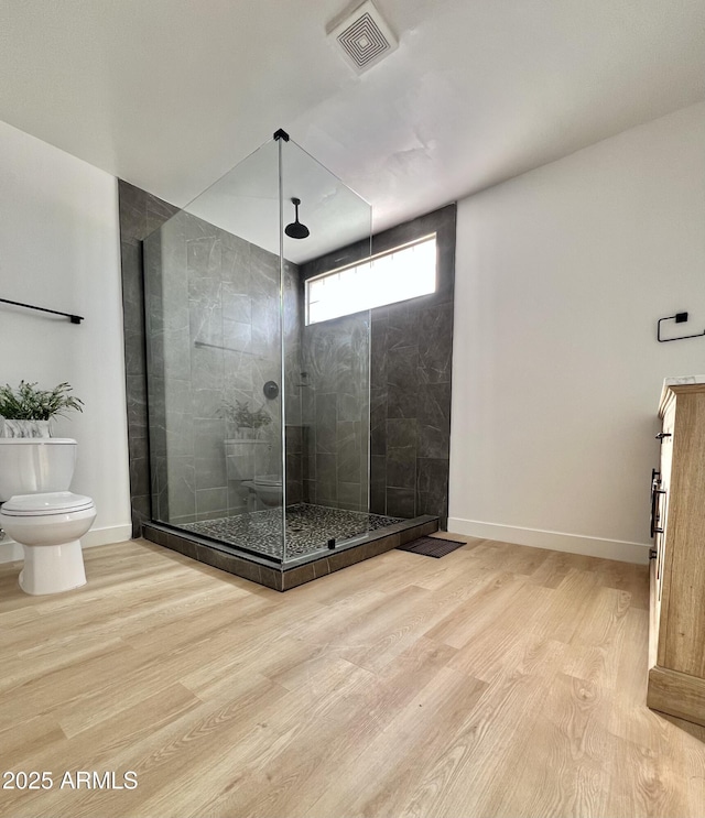 bathroom featuring toilet, hardwood / wood-style floors, and a shower with shower door