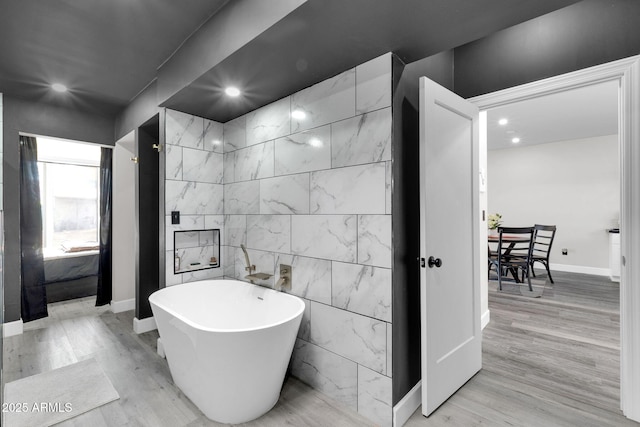 bathroom featuring a freestanding tub, recessed lighting, wood finished floors, and baseboards