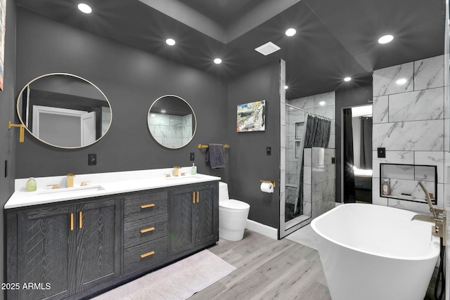 full bath featuring wood finished floors, tiled shower, double vanity, recessed lighting, and a sink