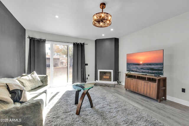 living room with wood finished floors, baseboards, recessed lighting, a large fireplace, and a chandelier