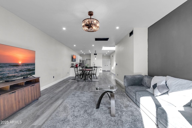 living area with recessed lighting, baseboards, a notable chandelier, and wood finished floors