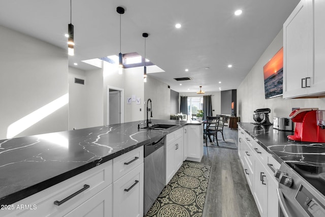 kitchen with visible vents, appliances with stainless steel finishes, wood finished floors, white cabinets, and a sink