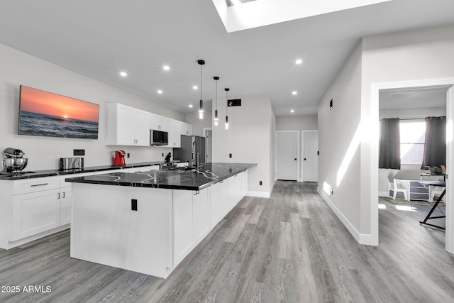 kitchen with light wood finished floors, appliances with stainless steel finishes, and white cabinetry