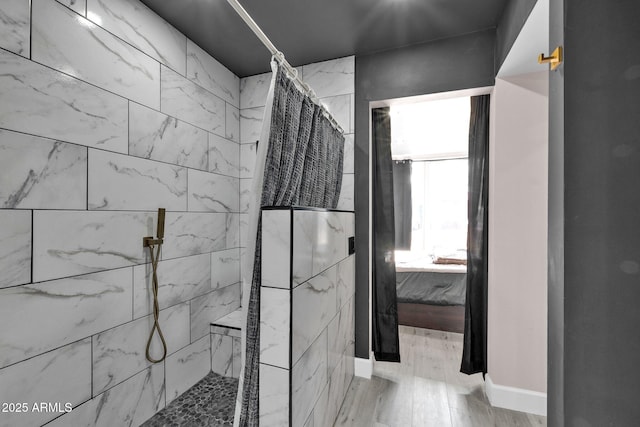 bathroom with baseboards, wood finished floors, and a walk in shower