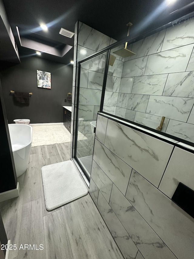 full bathroom with visible vents, a stall shower, vanity, and wood finished floors