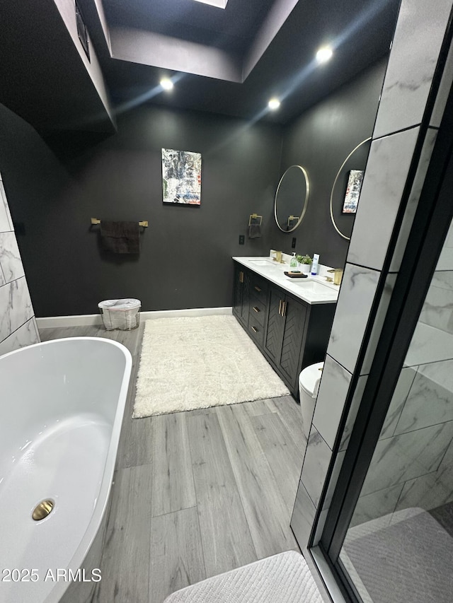 bathroom with double vanity, a stall shower, wood finished floors, and a washtub