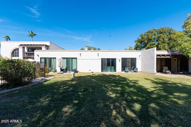 back of house with a lawn and stucco siding