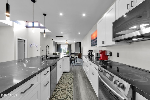 kitchen with pendant lighting, a sink, wood finished floors, stainless steel appliances, and white cabinets