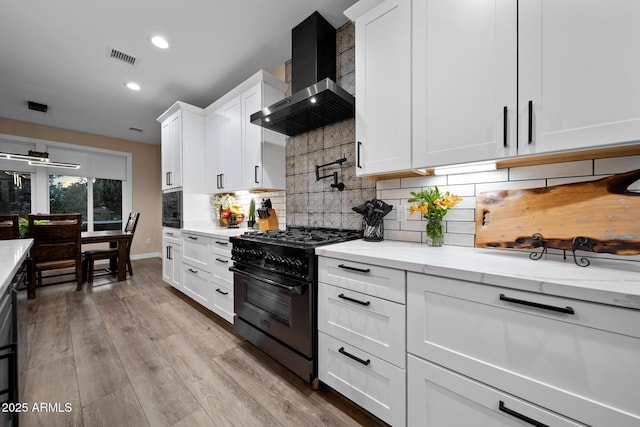 1500 W Pinetree Ct, Show Low, AZ 85901 - kitchen featuring black gas stove, wall chimney exhaust hood, tasteful backsplash, white cabinetry, and light stone counters