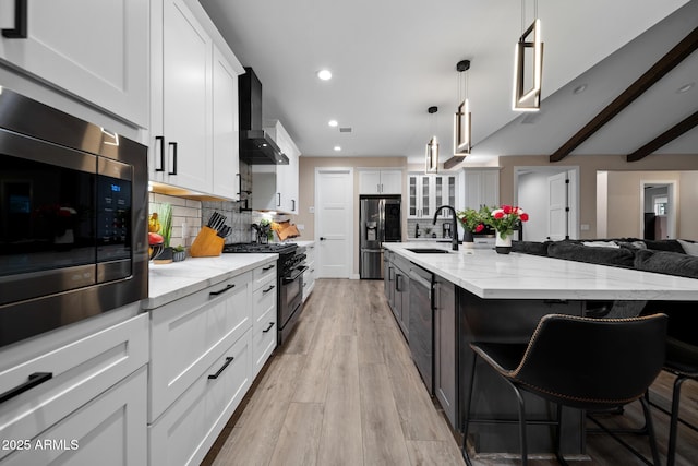 1500 W Pinetree Ct, Show Low, AZ 85901 - kitchen featuring appliances with stainless steel finishes, wall chimney range hood, decorative backsplash, white cabinets, and a breakfast bar area