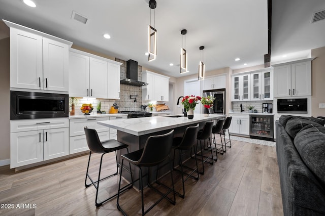 1500 W Pinetree Ct, Show Low, AZ 85901 - kitchen with built in microwave, wall chimney range hood, beverage cooler, backsplash, and light wood-style flooring