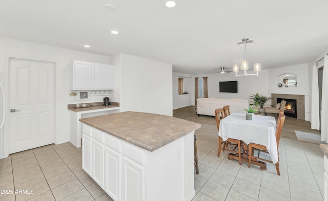 1821 E Patrick Ln, Phoenix, AZ 85024 - kitchen with light tile patterned flooring, a kitchen island, recessed lighting, a warm lit fireplace, and white cabinets