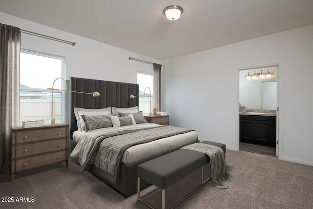 bedroom with dark colored carpet, baseboards, ensuite bathroom, and a sink