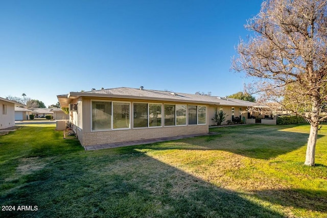 back of property with a yard and central AC