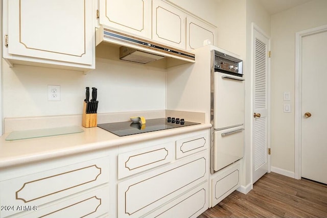 kitchen featuring white cabinets, white double oven, black electric cooktop, and hardwood / wood-style flooring