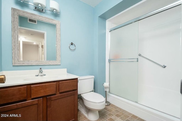 bathroom featuring a shower with door, vanity, and toilet