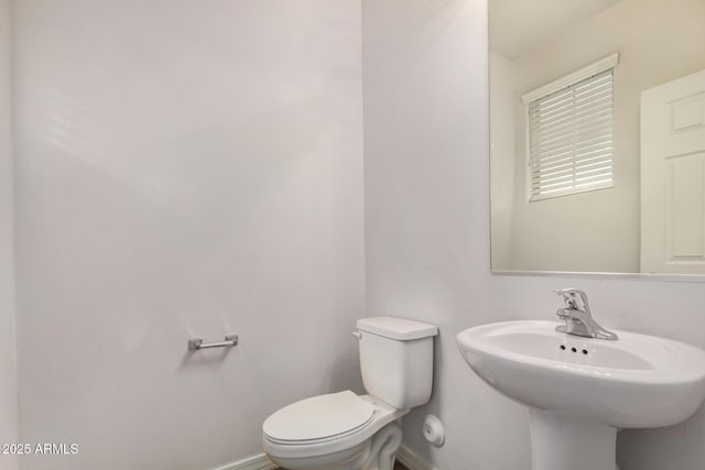 bathroom featuring a sink, toilet, and baseboards