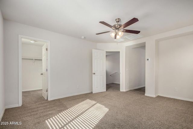 unfurnished bedroom with a closet, carpet flooring, baseboards, and a spacious closet