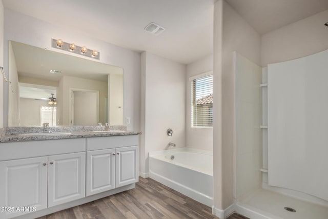 full bath with double vanity, visible vents, a sink, and wood finished floors