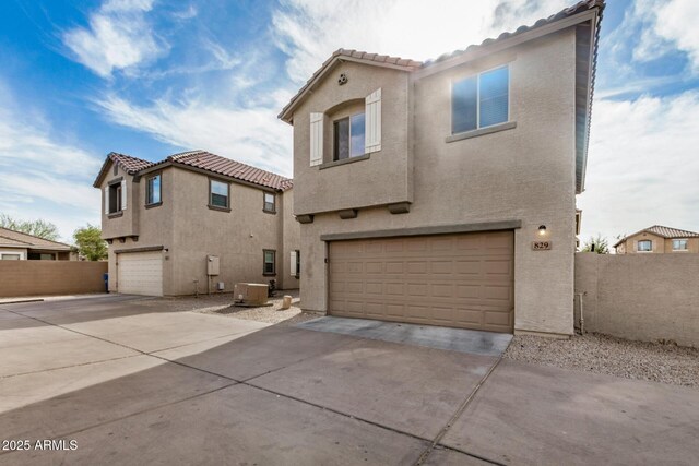 view of front facade with a tiled roof, central AC, stucco siding, a garage, and concrete driveway