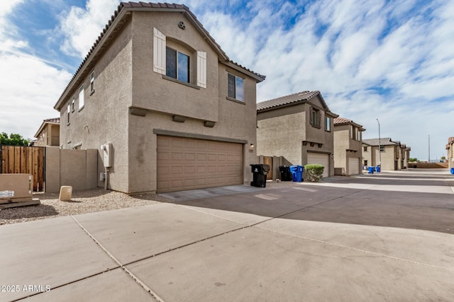exterior space with stucco siding, fence, a tile roof, a garage, and concrete driveway