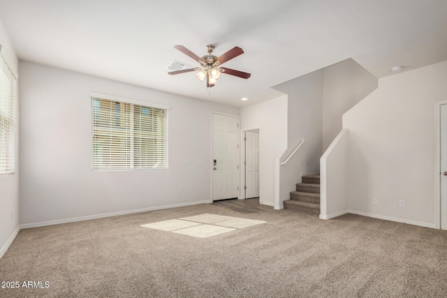 carpeted spare room featuring visible vents, baseboards, a ceiling fan, and stairway
