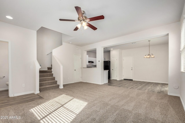 unfurnished living room featuring ceiling fan with notable chandelier, carpet, recessed lighting, stairs, and baseboards