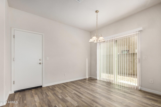 spare room featuring baseboards, an inviting chandelier, and wood finished floors