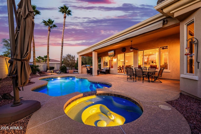 view of swimming pool featuring ceiling fan, outdoor dining area, a pool with connected hot tub, a patio area, and a fenced backyard