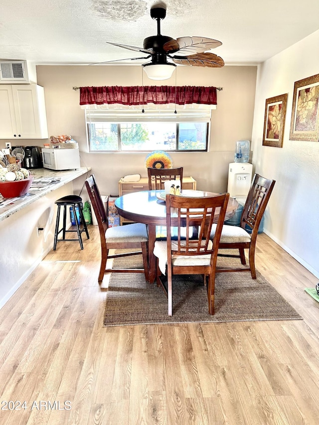 dining area featuring ceiling fan, light hardwood / wood-style floors, and a textured ceiling