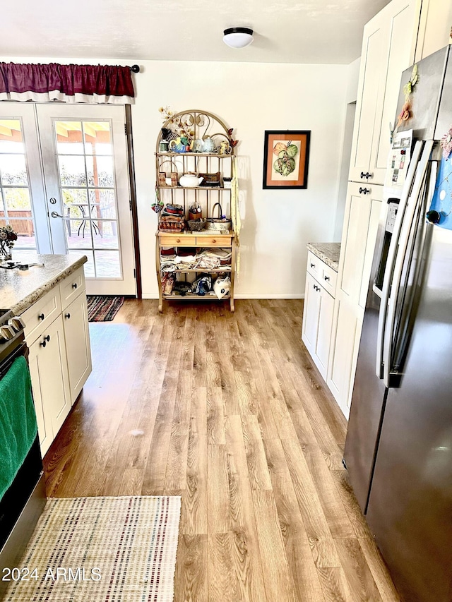 kitchen with white cabinets, light hardwood / wood-style floors, light stone counters, and appliances with stainless steel finishes