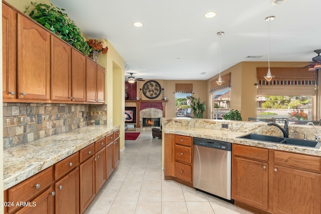 kitchen with backsplash, sink, stainless steel dishwasher, light tile patterned floors, and decorative light fixtures