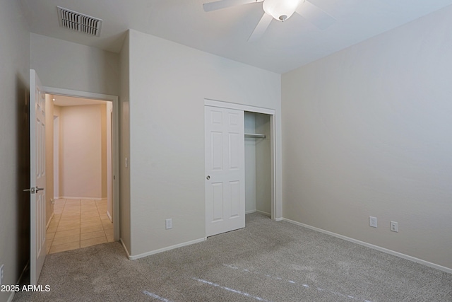 unfurnished bedroom with ceiling fan, light colored carpet, and a closet