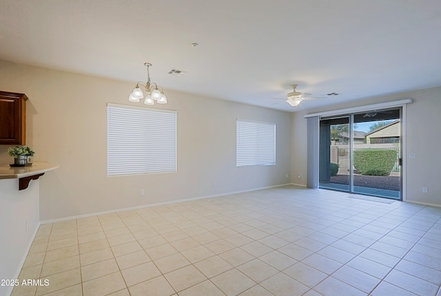 tiled spare room with ceiling fan with notable chandelier