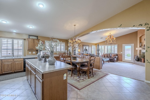 kitchen featuring vaulted ceiling, hanging light fixtures, light carpet, sink, and a kitchen island