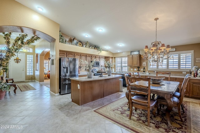 kitchen featuring lofted ceiling, a notable chandelier, a kitchen island, pendant lighting, and appliances with stainless steel finishes