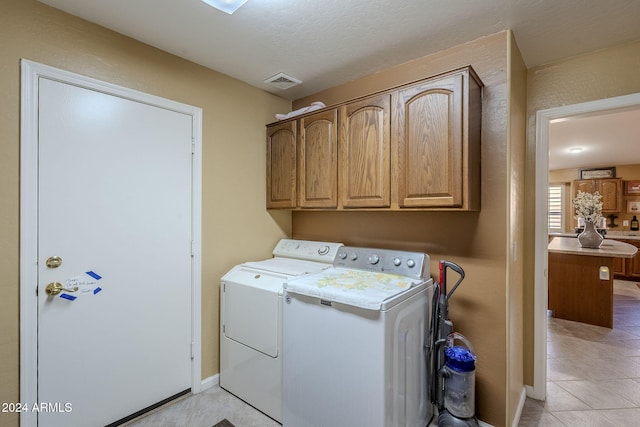 washroom featuring cabinets, independent washer and dryer, light tile patterned floors, and a textured ceiling