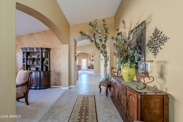 hall with vaulted ceiling and light tile patterned floors