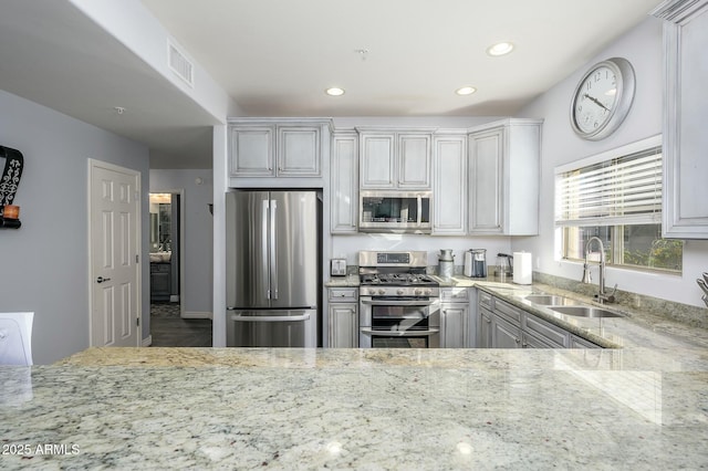 kitchen featuring stainless steel appliances, light stone countertops, and sink