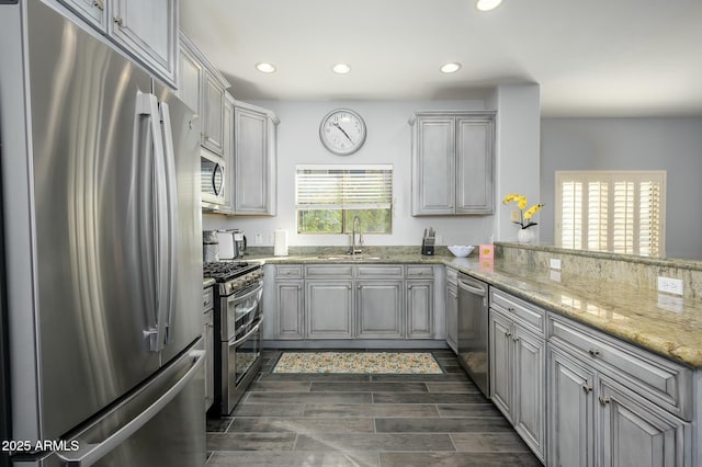 kitchen featuring gray cabinets, appliances with stainless steel finishes, sink, light stone counters, and plenty of natural light