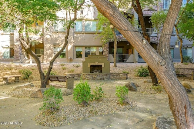 rear view of property featuring an outdoor stone fireplace