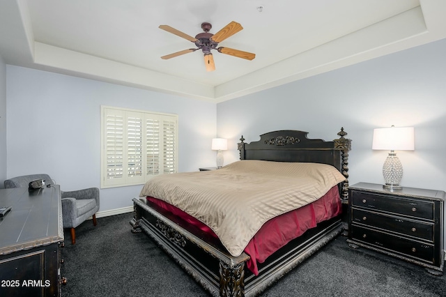 bedroom featuring dark carpet, ceiling fan, and a tray ceiling