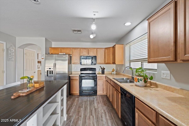 kitchen featuring pendant lighting, sink, hardwood / wood-style floors, black appliances, and a textured ceiling