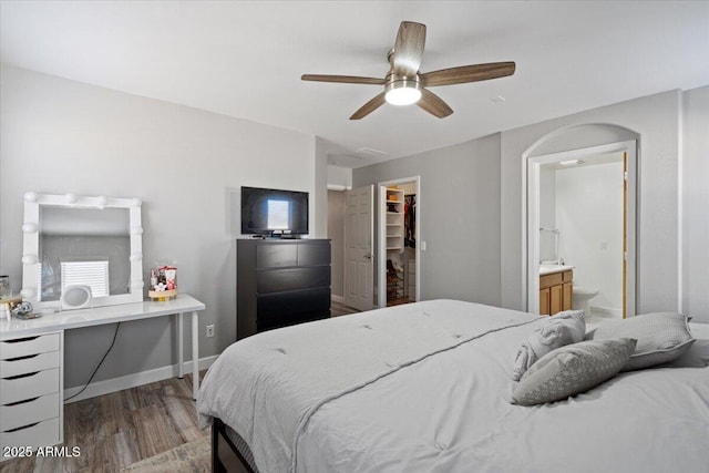 bedroom featuring a spacious closet, ceiling fan, light hardwood / wood-style floors, ensuite bath, and a closet