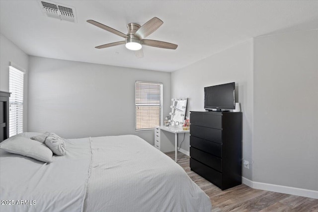 bedroom with multiple windows, wood-type flooring, and ceiling fan