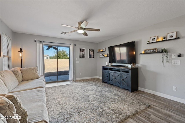 living room with a textured ceiling, wood-type flooring, and ceiling fan