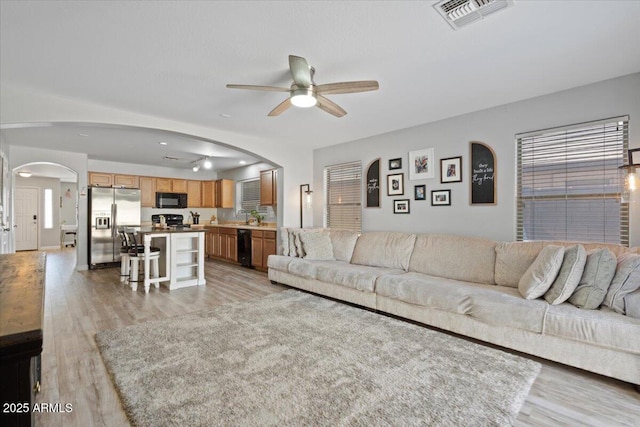 living room with sink, light hardwood / wood-style floors, and ceiling fan